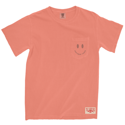 Coral t-shirt with a smiley face design on the pocket